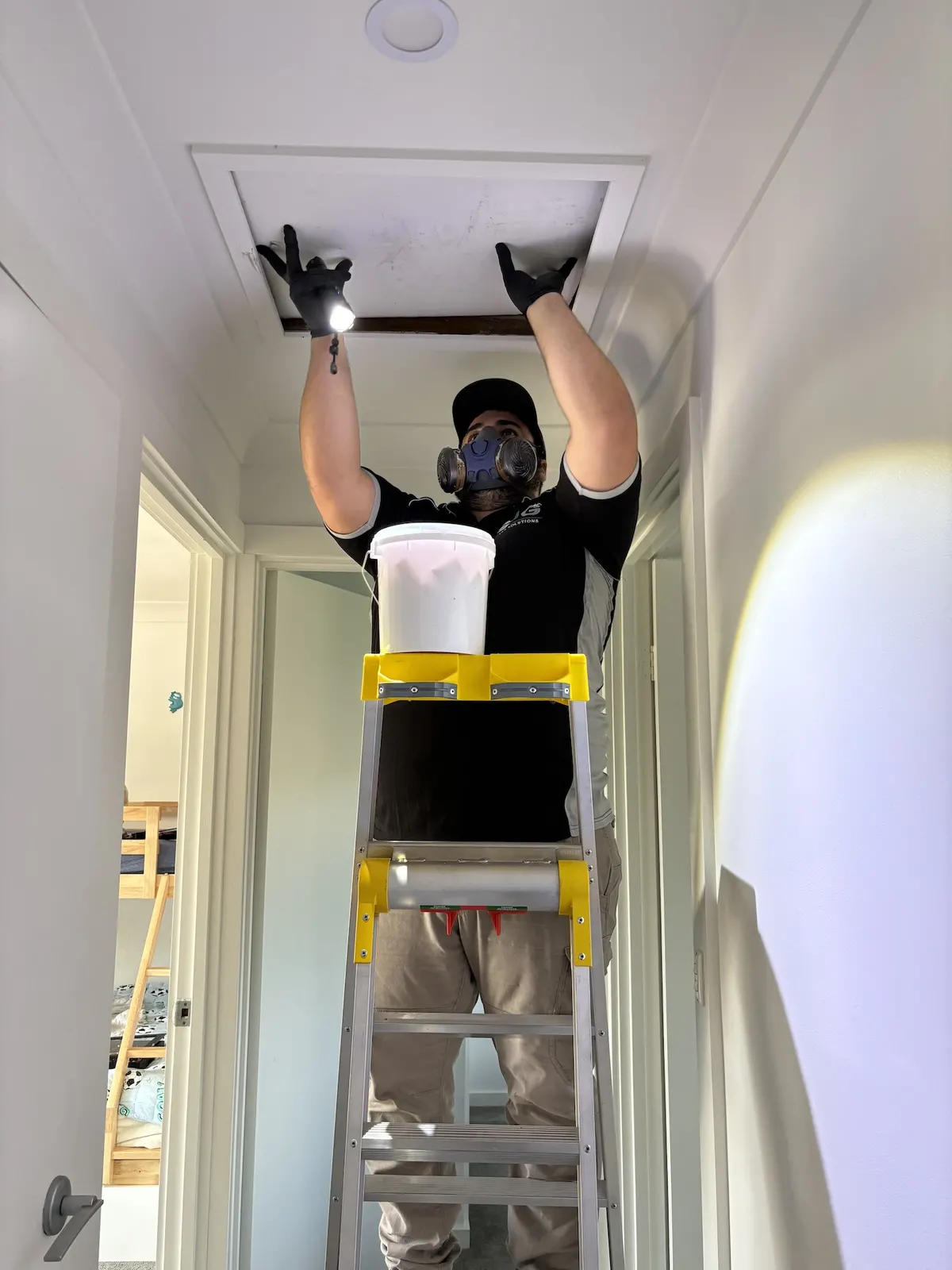SJG technician treating a roof void through the manhole during a home pest service